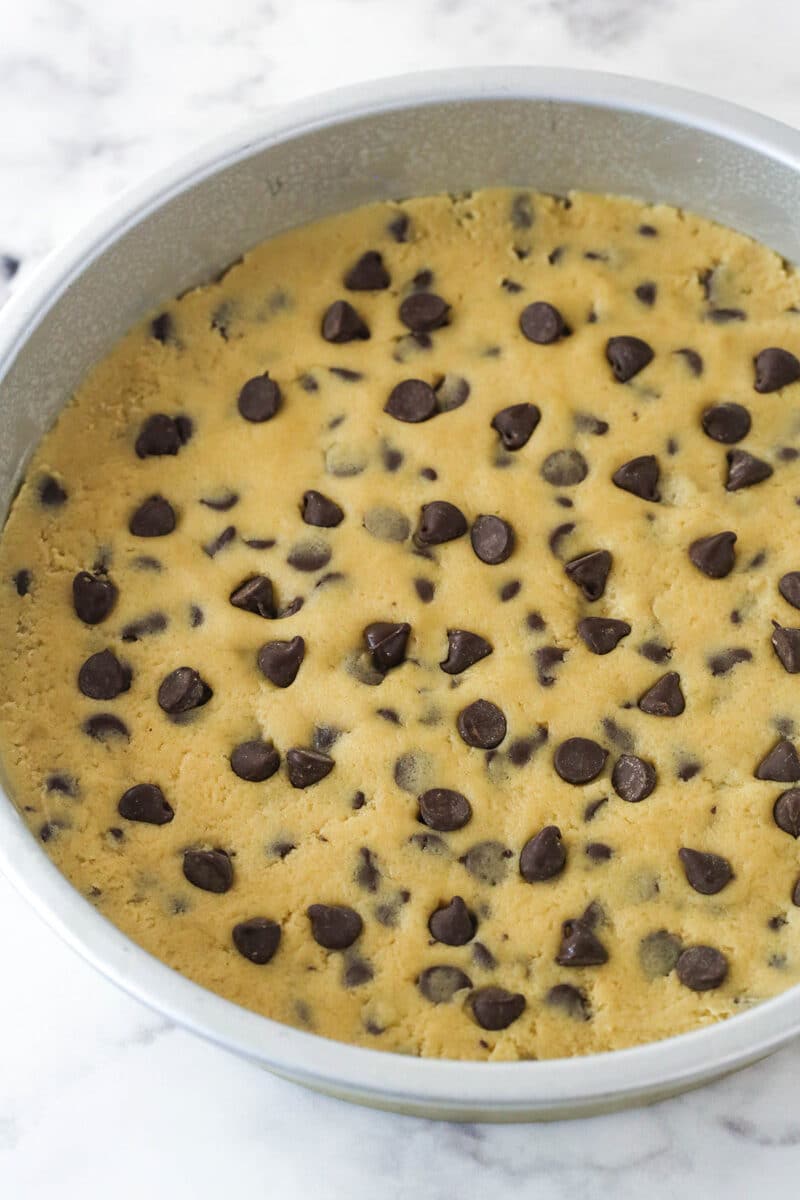Chocolate chip cookie dough in a cake pan.