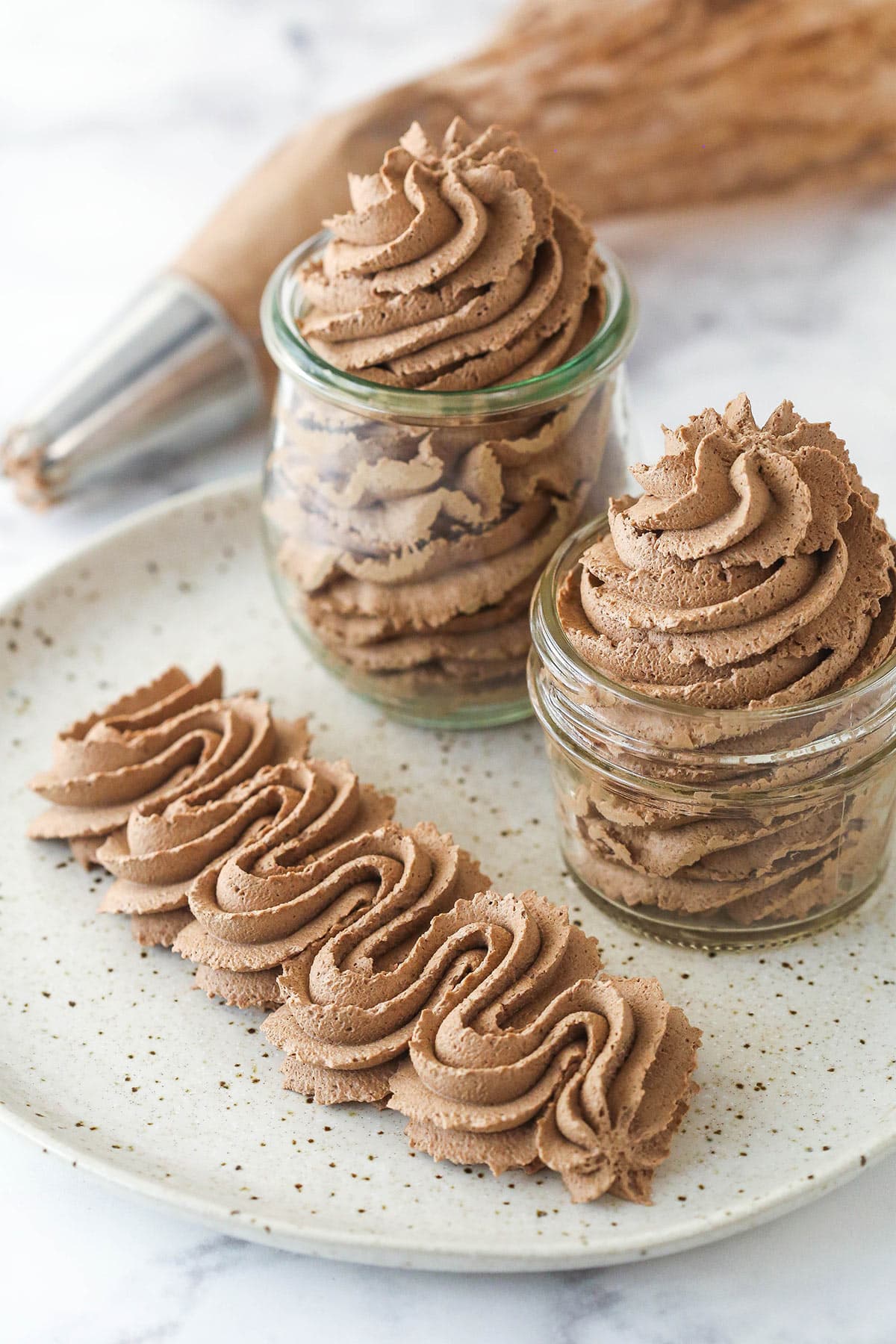 Chocolate whipped cream in jars and piped onto a plate.