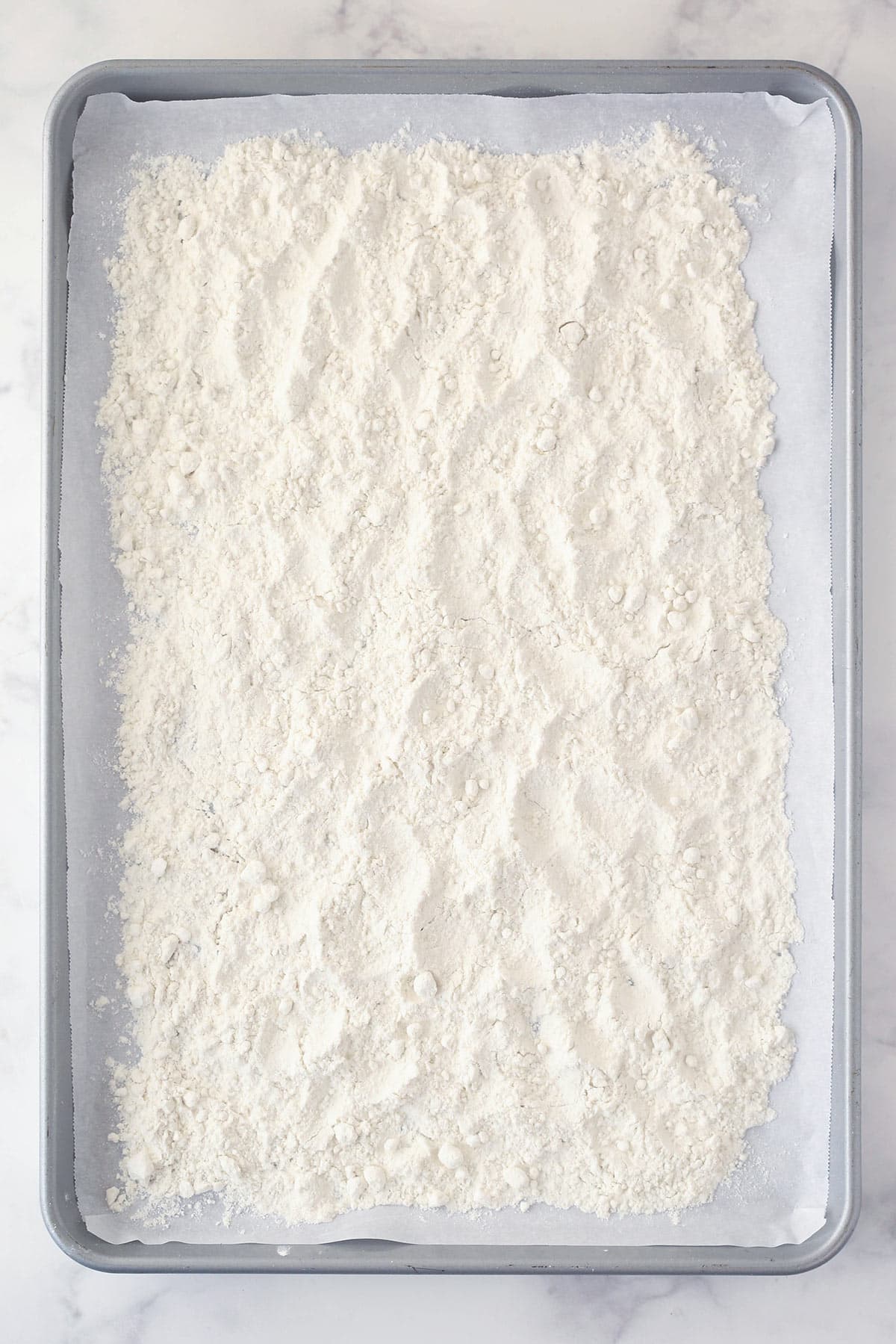 Flour spread out on a baking sheet lined with parchment paper.