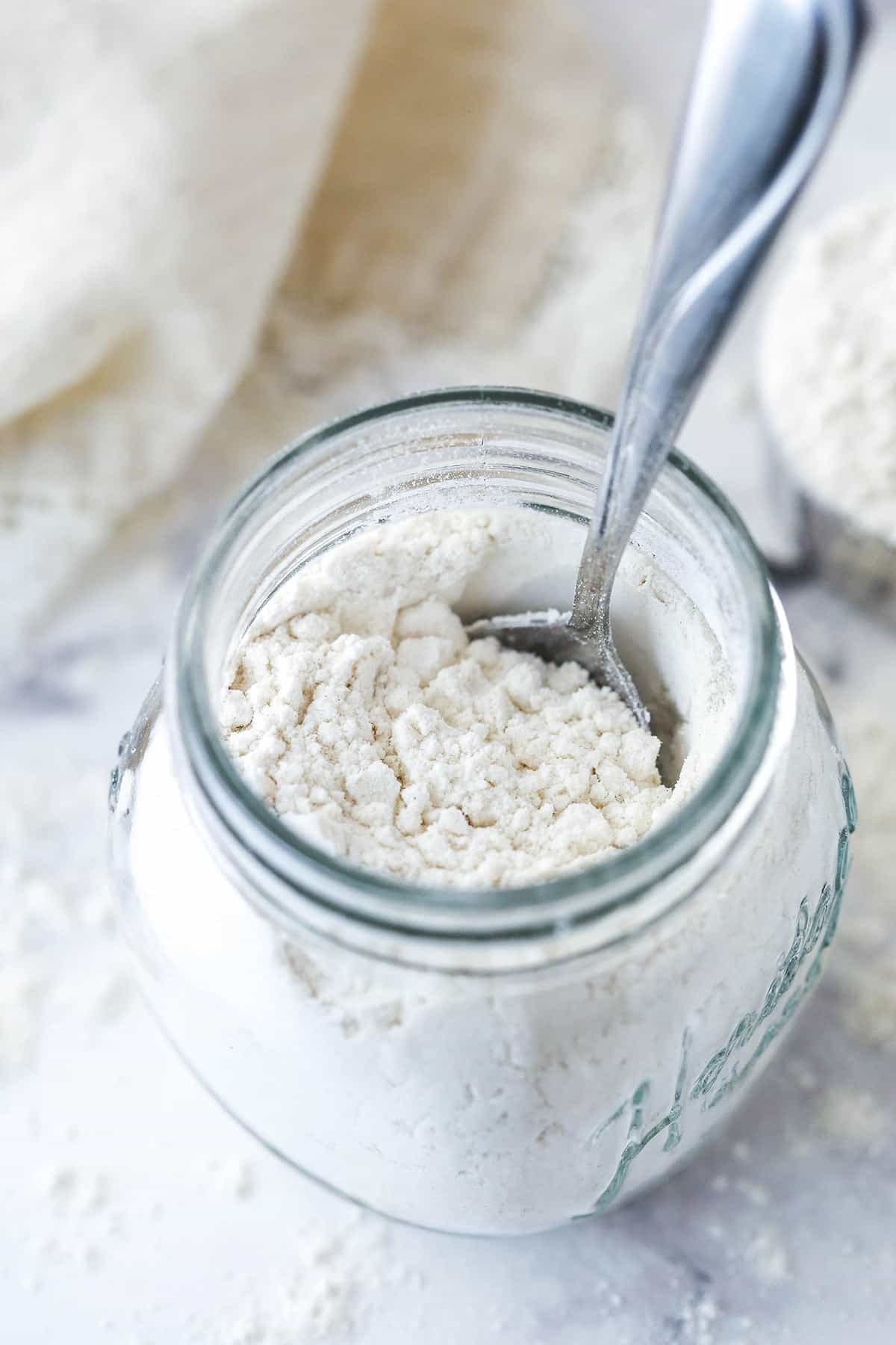 Closeup of a spoon in a jar of heat treated flour.