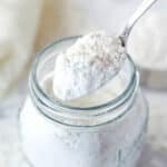 A spoon scooping heat treated flour out of a jar.