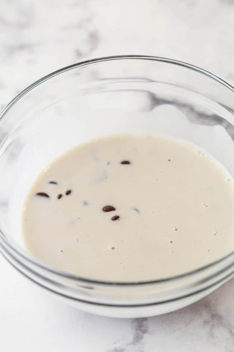 Pouring hot heavy cream over chocolate chips to make chocolate ganache.