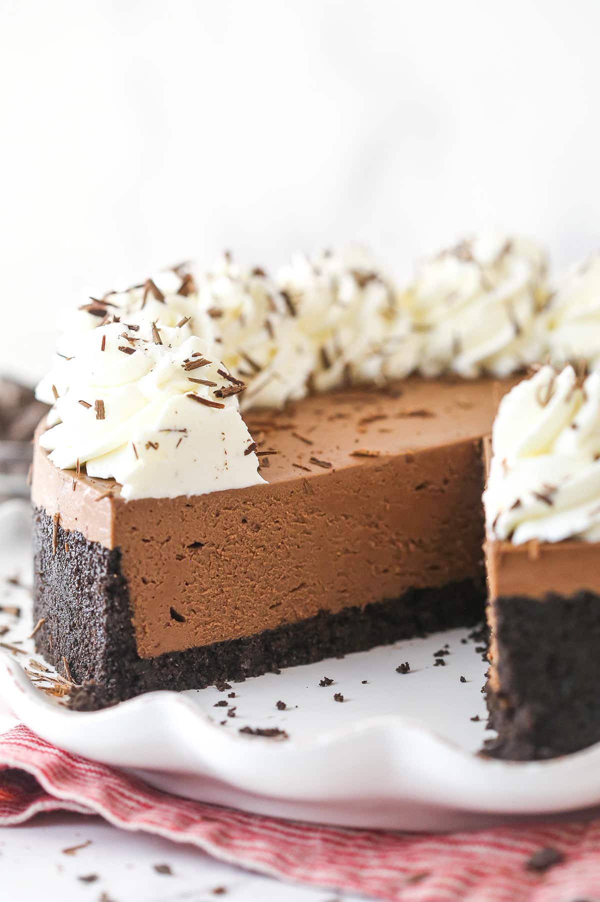 A No-Bake Chocolate Cheesecake on a white serving plate with a slice removed to show texture.