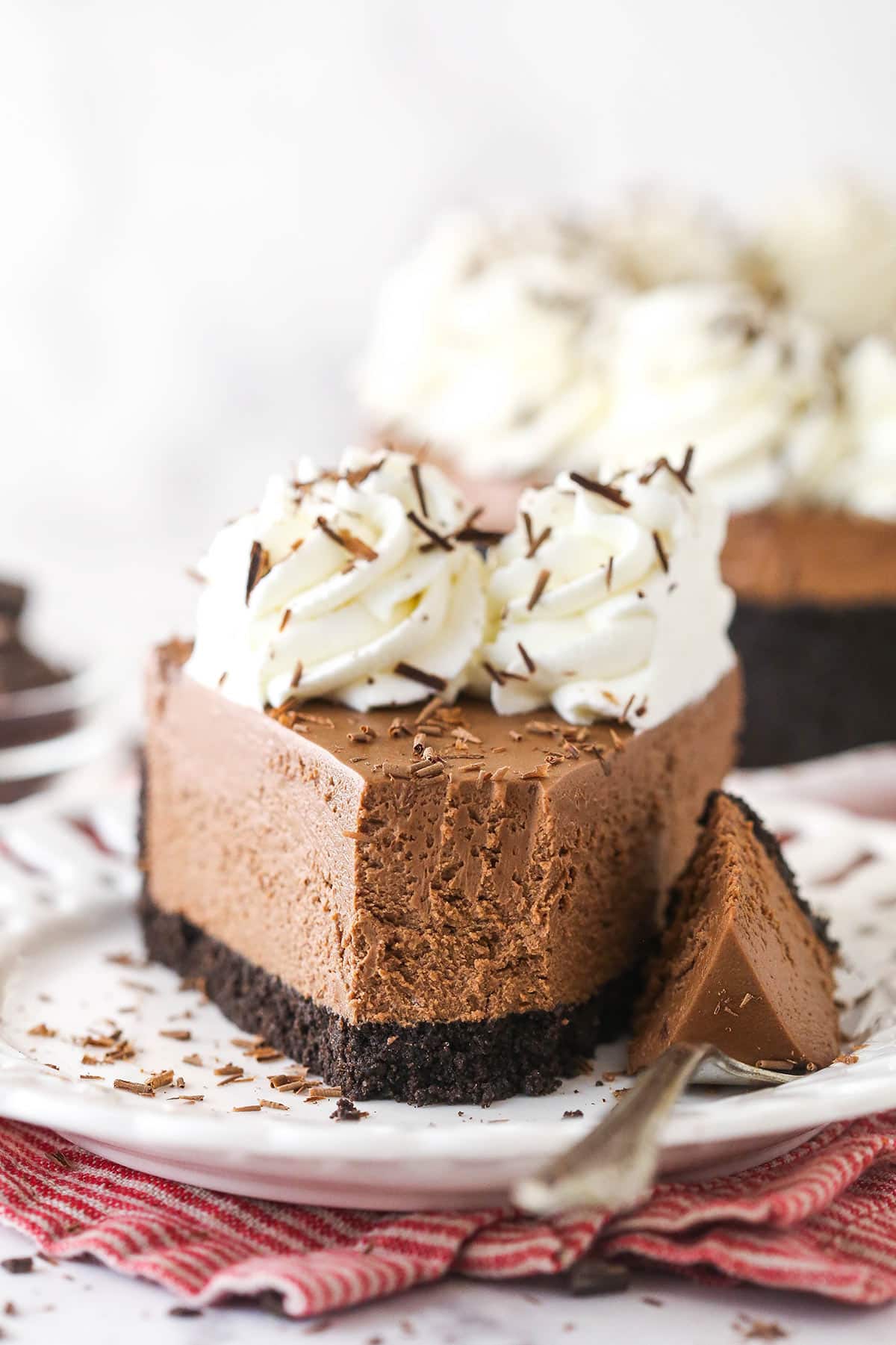 A slice of No-Bake Chocolate Cheesecake on a plate with a bite removed on a fork.