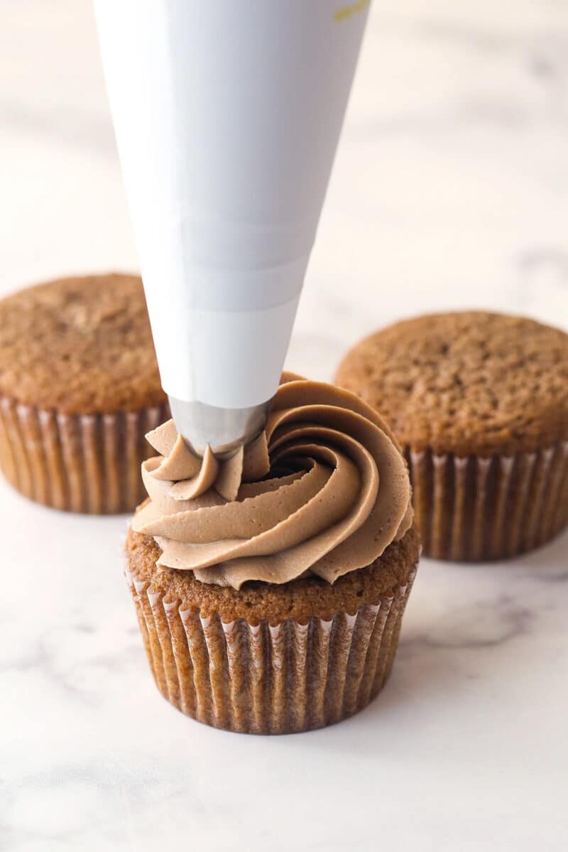 Piping Nutella buttercream onto Nutella cupcakes.