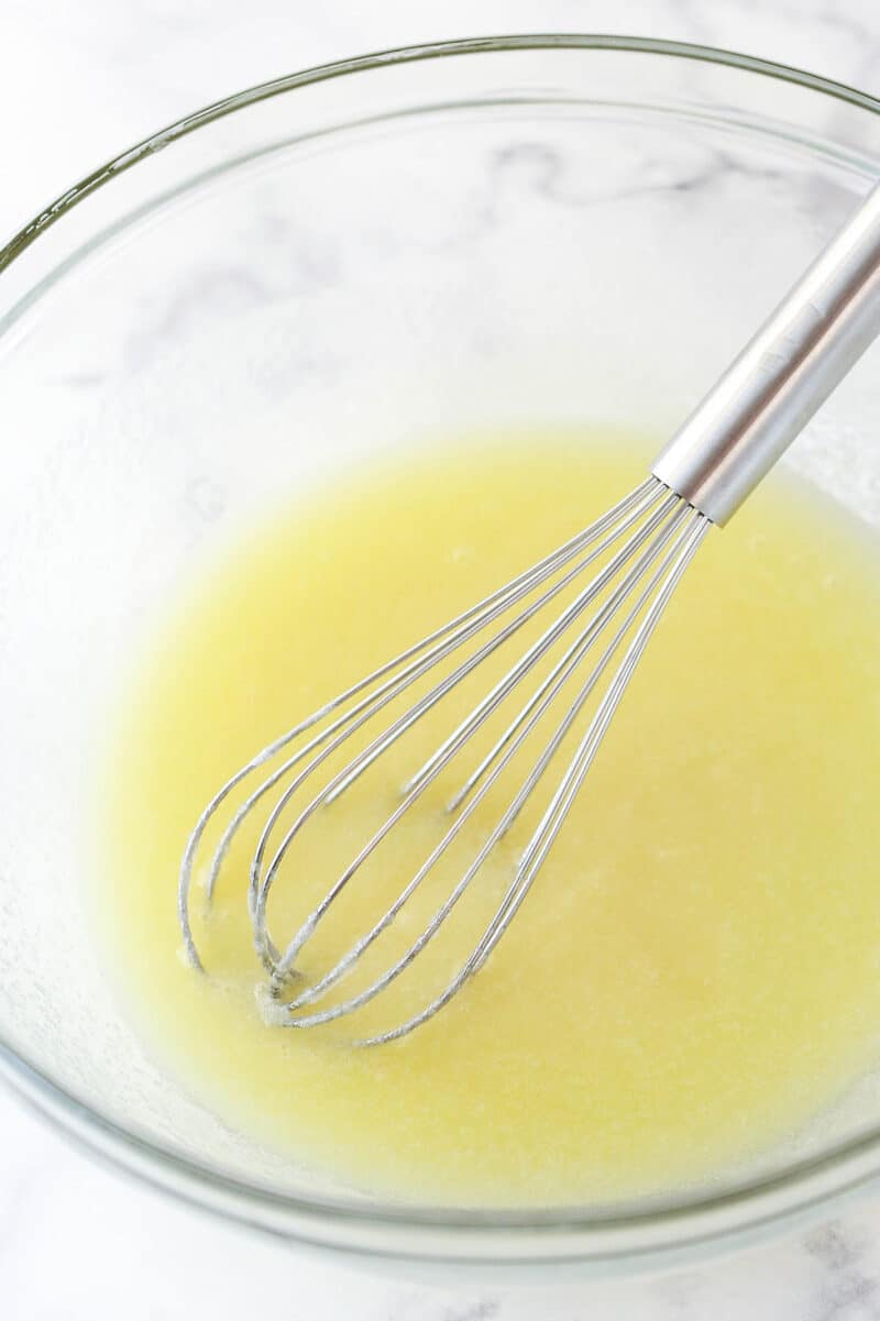 Whisking together melted butter, sugar, and vanilla.
