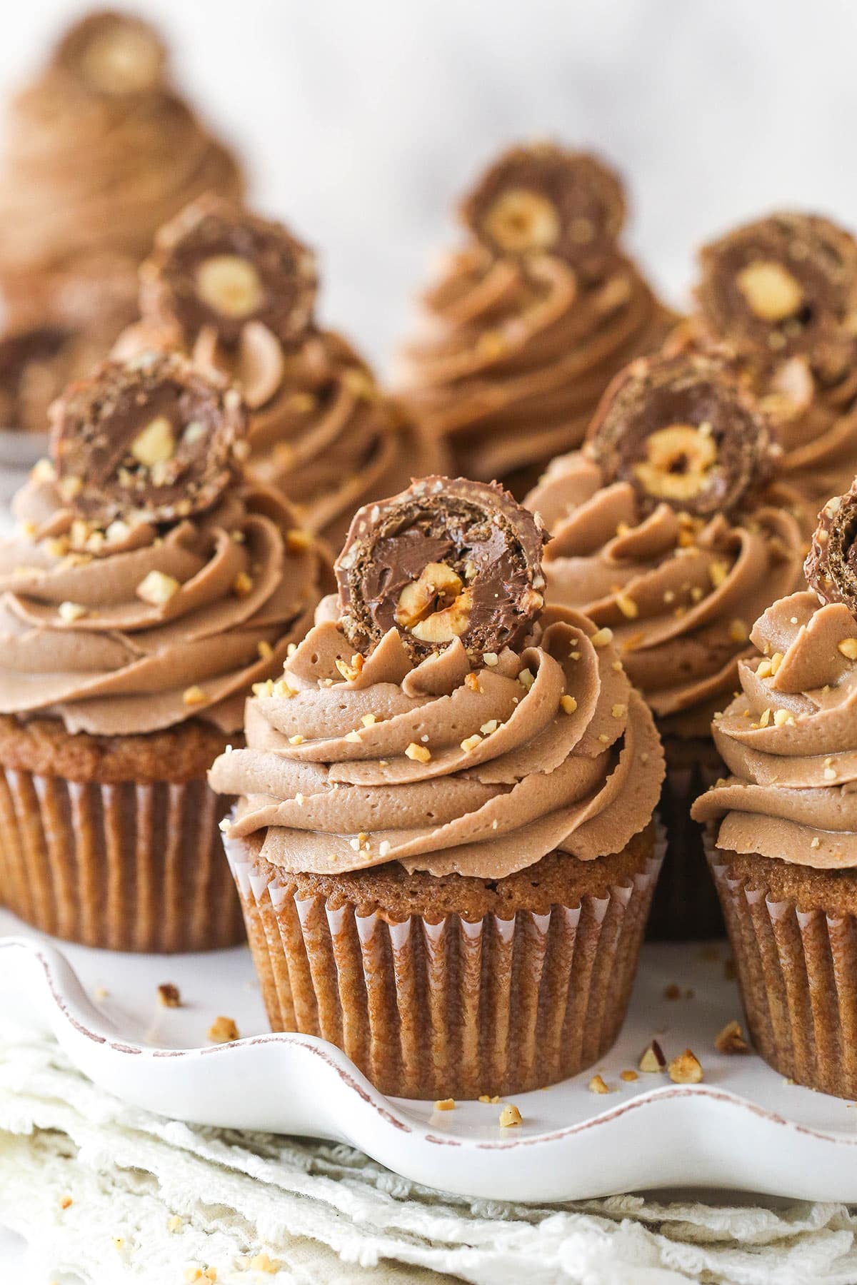 Nutella cupcakes on a serving platter garnished with chocolate hazelnut candies.