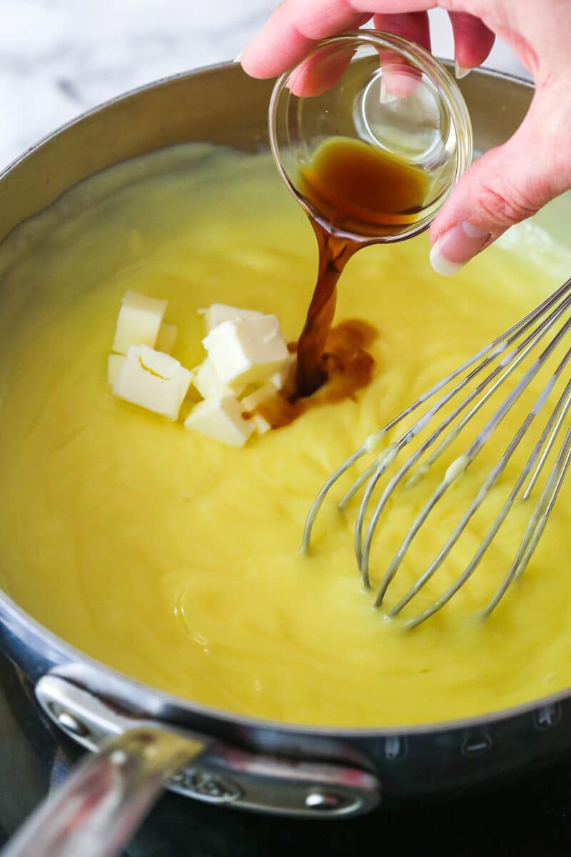 Adding vanilla and butter to pastry cream in a saucepan.