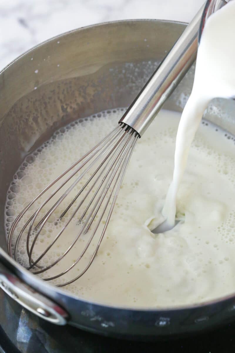 Whisking milk into cornstarch and sugar in a saucepan.
