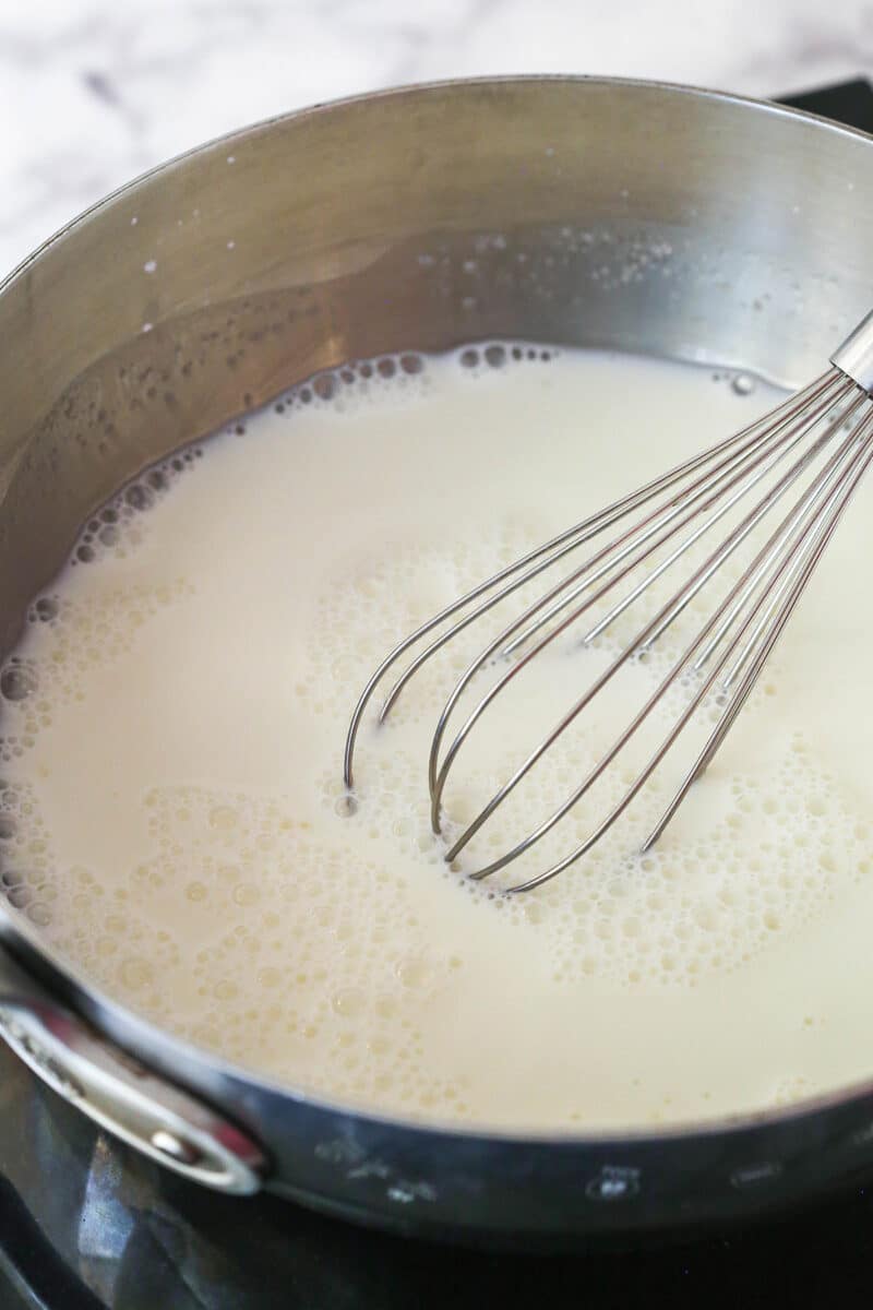 Lightly simmering a mixture of cornstarch, sugar, and milk in a saucepan.
