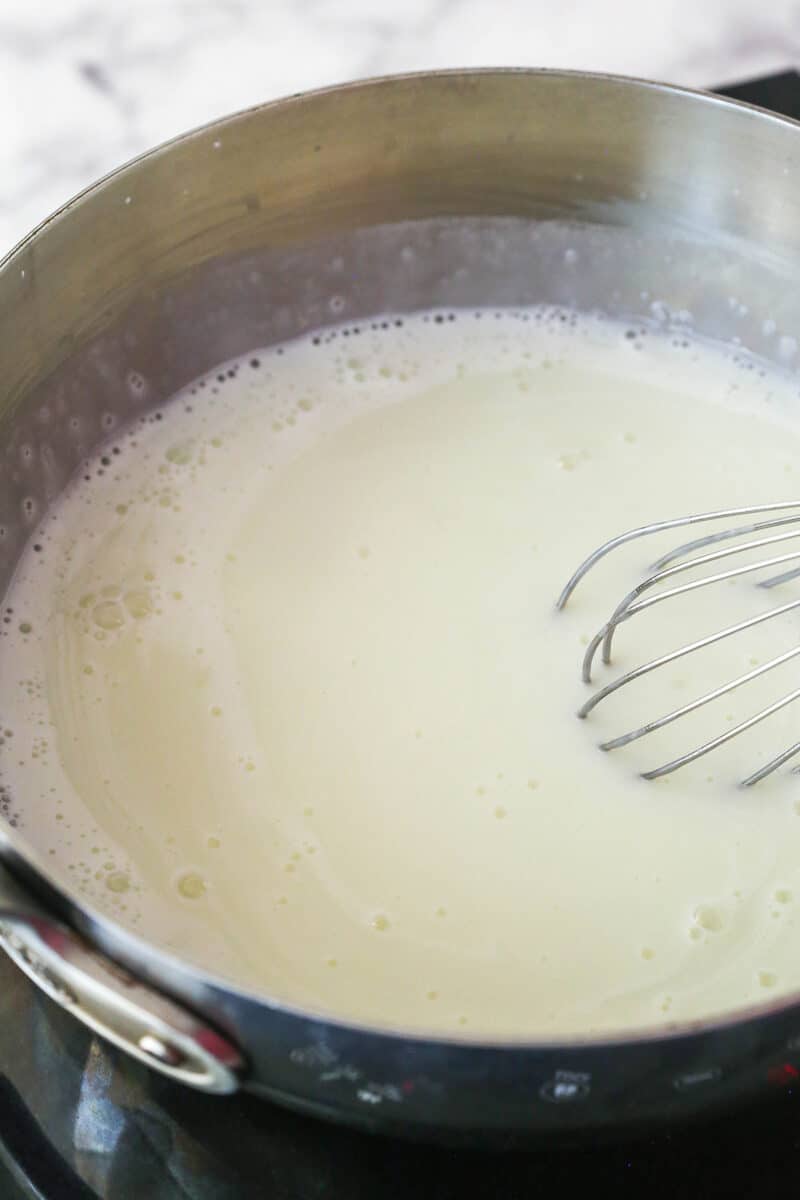 Lightly simmering a mixture of cornstarch, sugar, and milk in a saucepan.