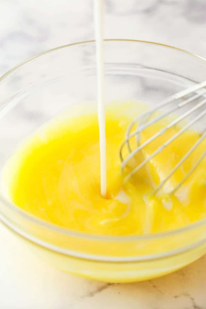 Tempering egg yolks with warm milk mixture.