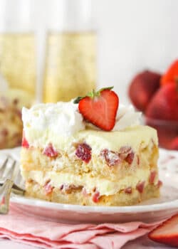 A slice of Strawberry Champagne Tiramisu on a white plate and pink napkin.