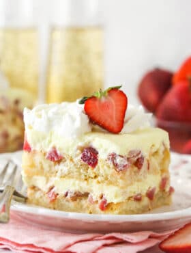 A slice of Strawberry Champagne Tiramisu on a white plate and pink napkin.