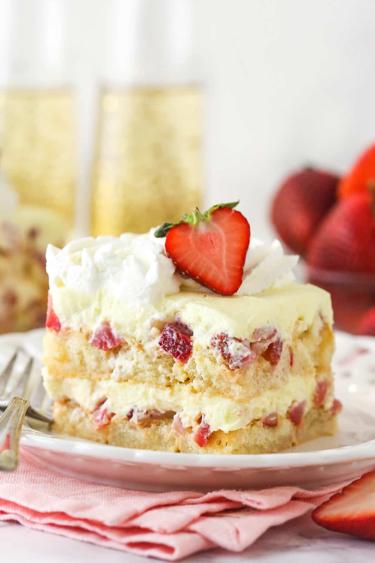 A slice of Strawberry Champagne Tiramisu on a white plate and pink napkin.