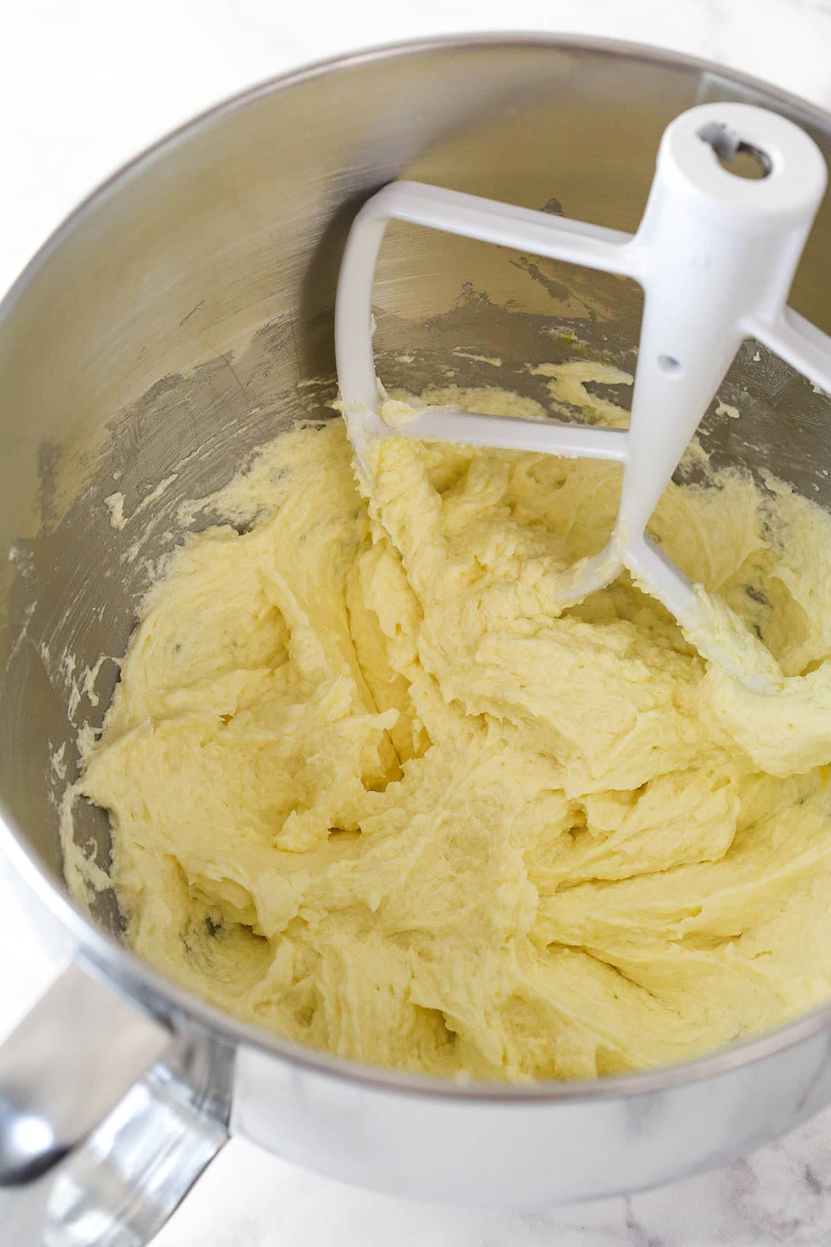 Overhead view of eggs combined with batter in a large mixing bowl