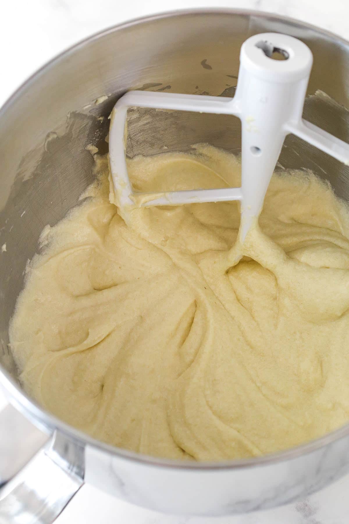 Overhead view of dry ingredients and milk combined to batter in a large mixing bowl