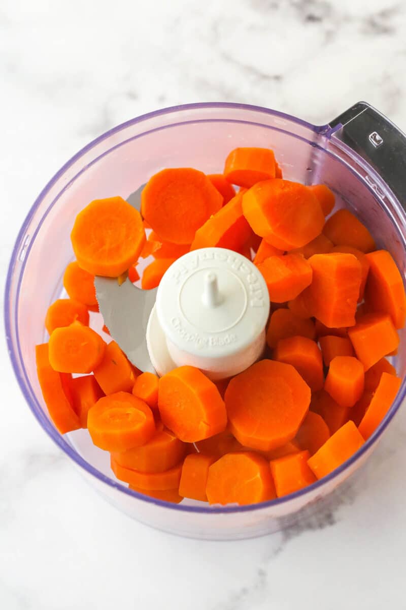 Adding streamed carrots to a food processor.