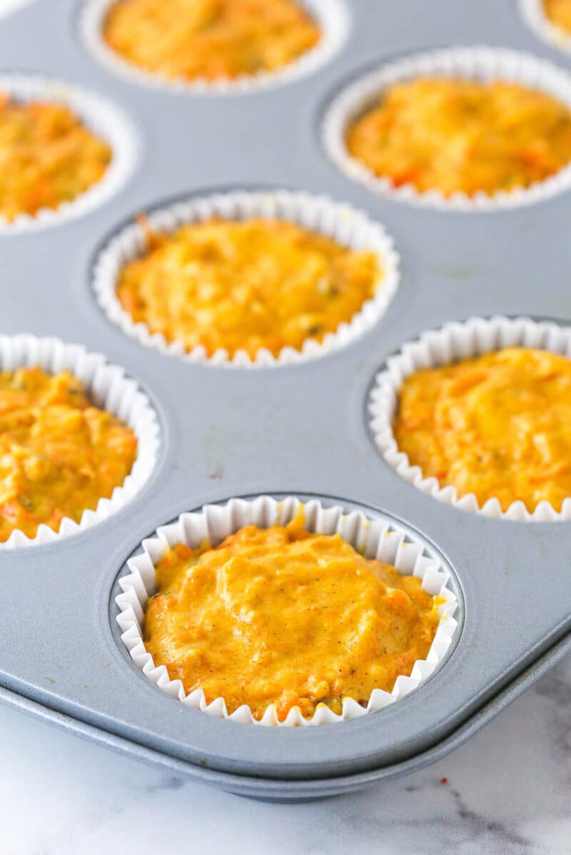 Cupcake liners in a cupcake pan filled with carrot cake cupcake batter.