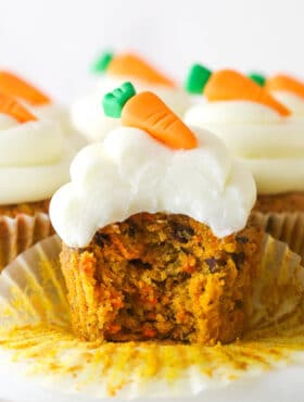 A carrot cake cupcake with a bite taken out of it.