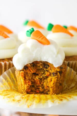 A carrot cake cupcake with a bite taken out of it.