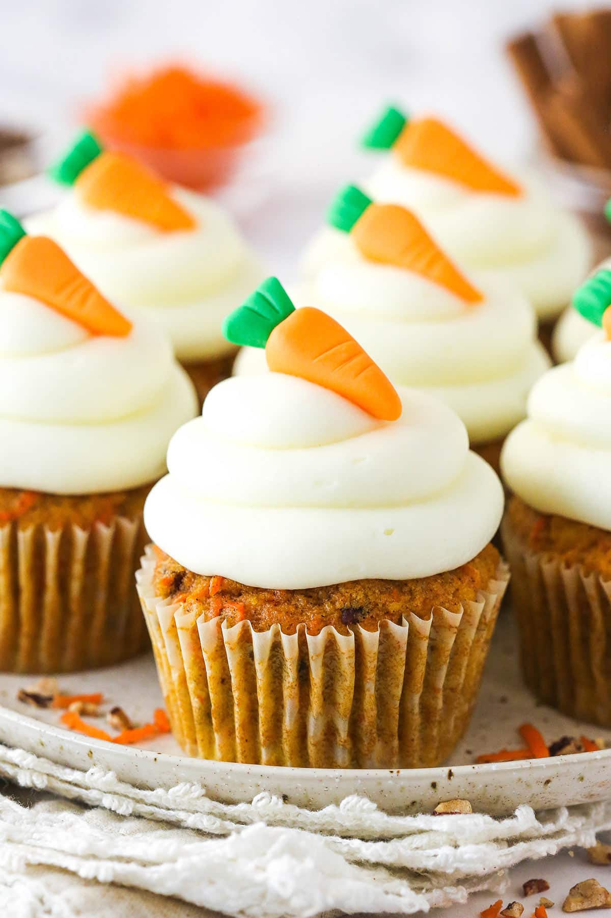 Carrot cake cupcakes on a serving platter topped with mini carrot toppers.