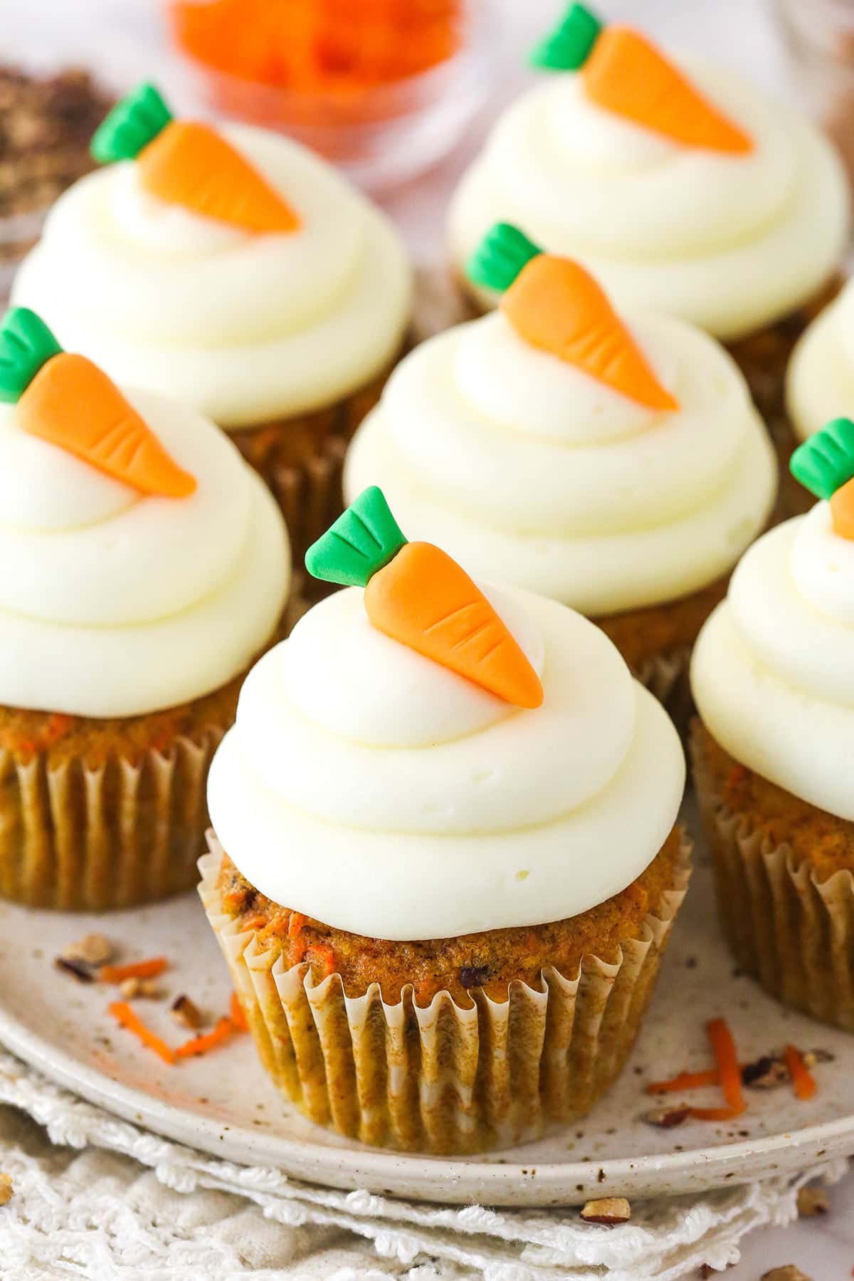 These moist carrot cake cupcakes are loaded with warm spices, teaming with exciting mix-ins, and topped with the best cream cheese frosting. Carrot cake cupcakes on a serving platter.