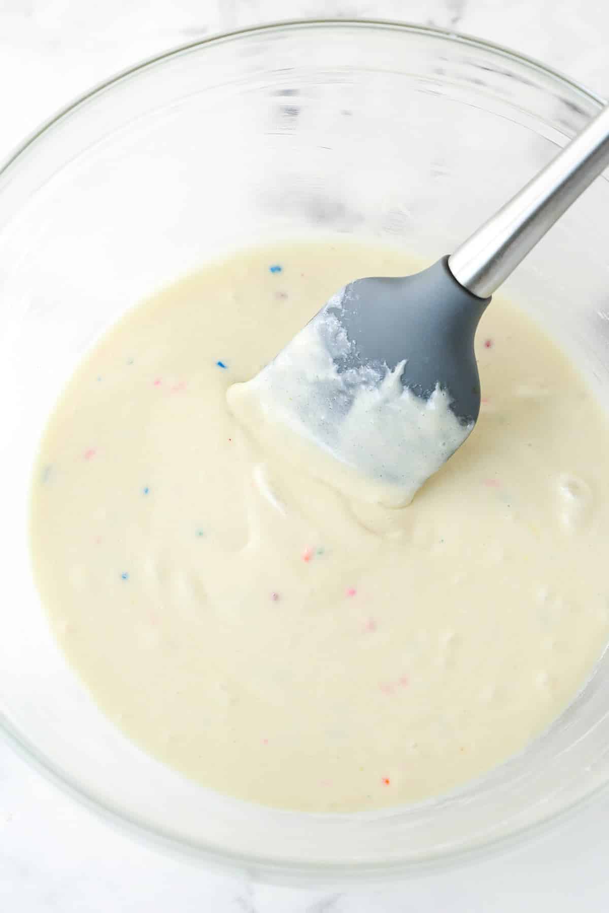 Mixing together sweetened condensed milk, milk, cooled cake mix, and vanilla extract.
