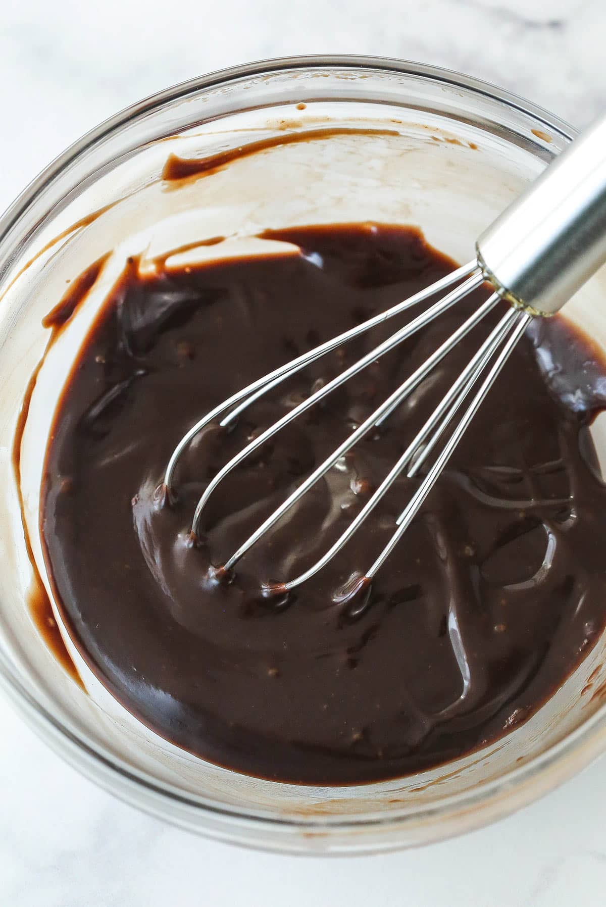 Whisking chocolate fudge sauce until smooth.