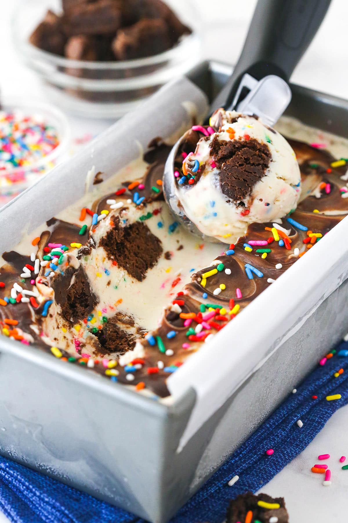 Scooping birthday cake ice cream out of a loaf pan.