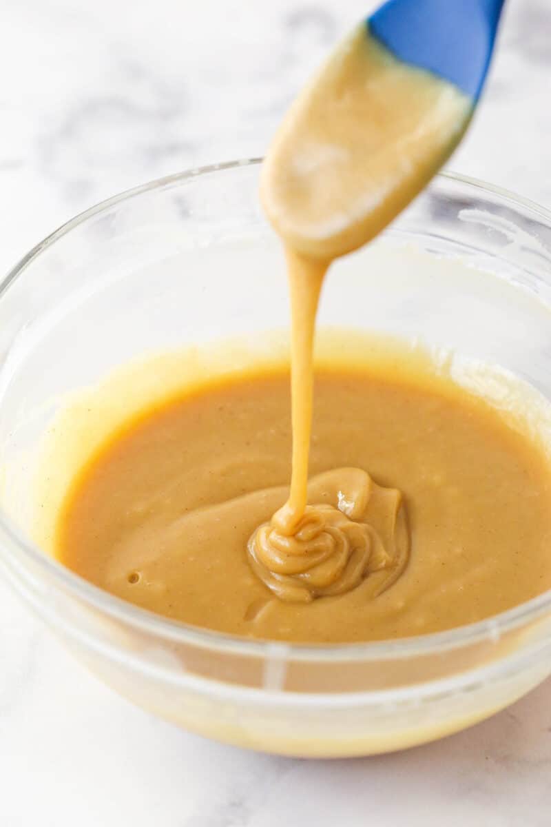 Drizzling peanut butter ganache in a mixing bowl.