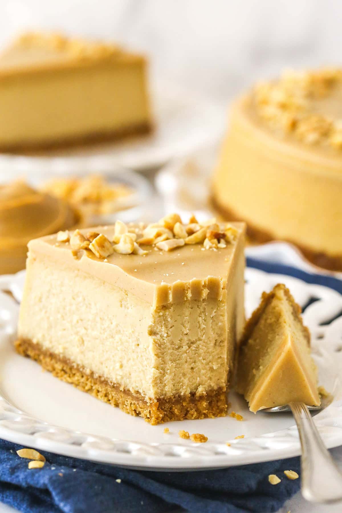 A fork taking a bite out of a slice of peanut butter cheesecake.