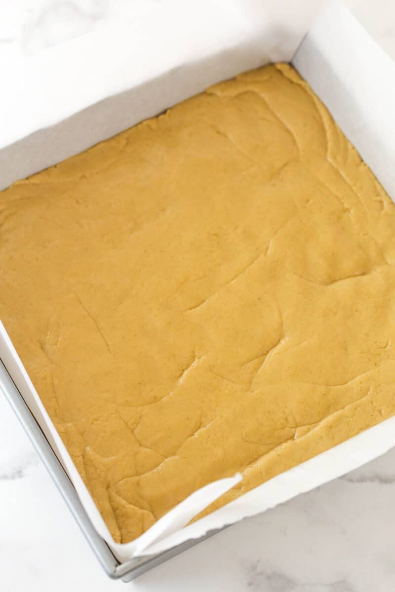 Peanut butter fudge in a baking dish lined with parchment paper.