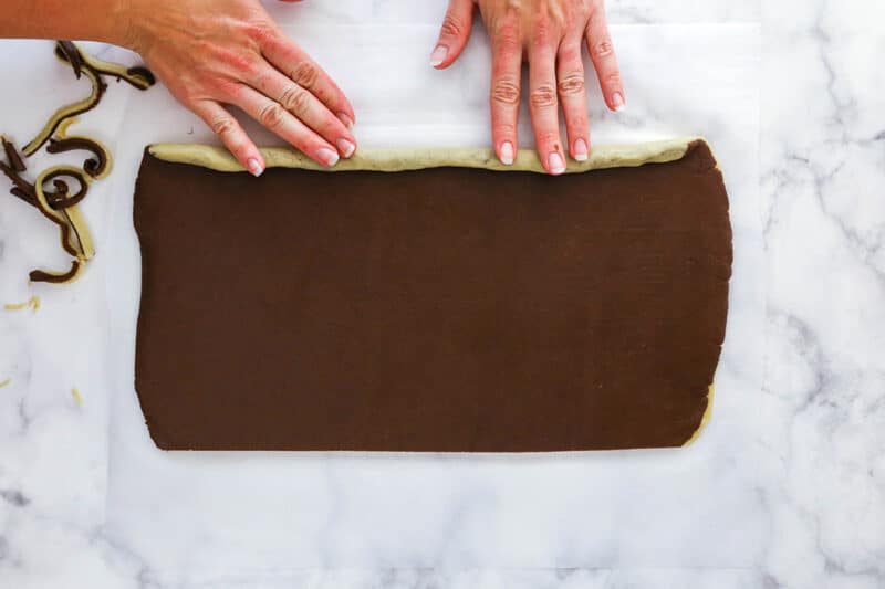 Rolling chocolate and vanilla cookie dough into a log.