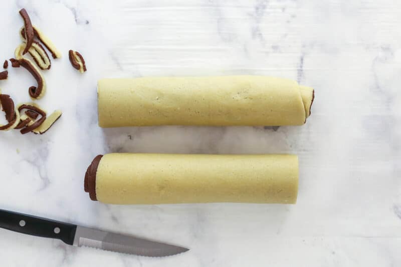 Cutting a log of pinwheel cookie dough in half.