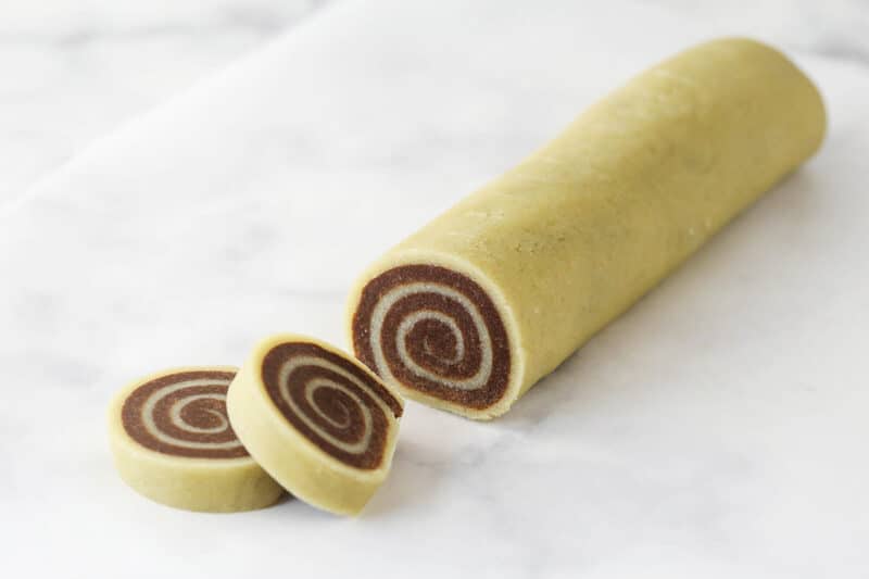 Slicing a log of pinwheel cookie dough into rounds.