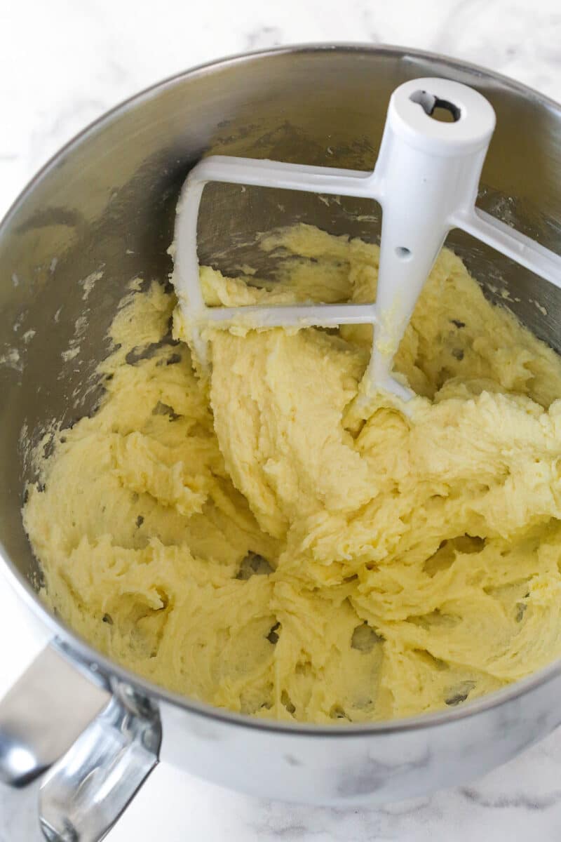 Mixing eggs and vanilla into creamed butter and sugar to make cookie dough.