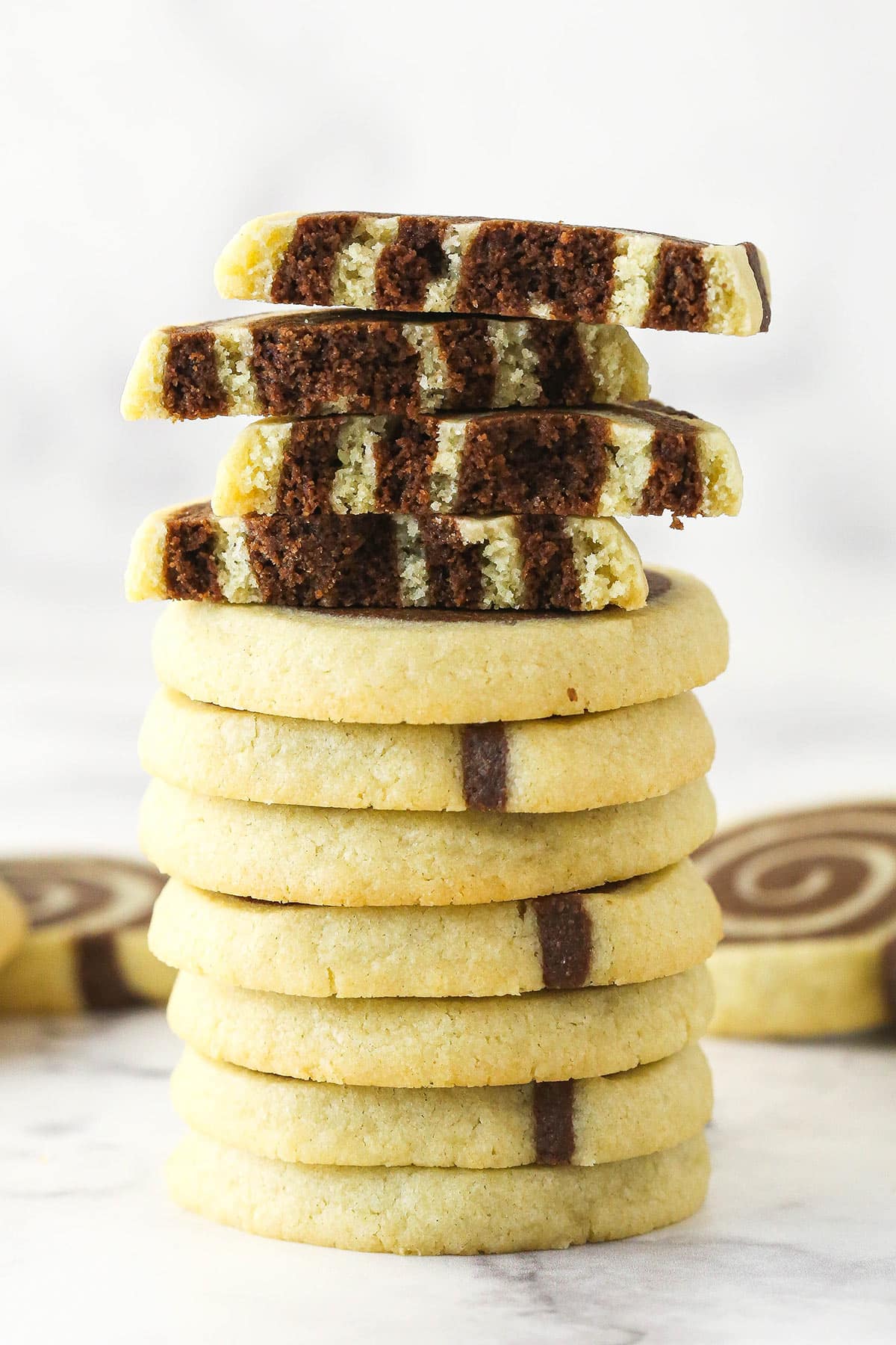A stack of pinwheel cookies. The top two cookies are broken in half.