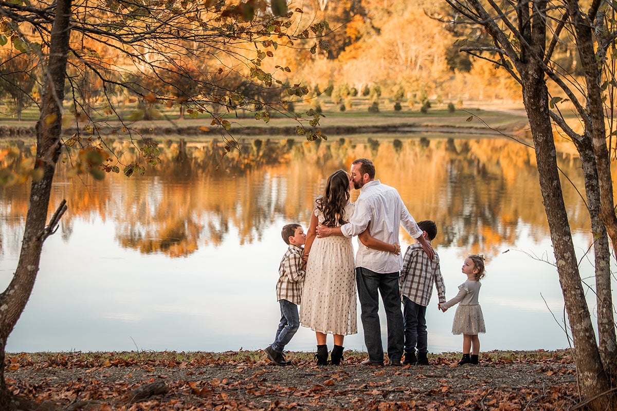 family standing by pond, mom and dad kissing