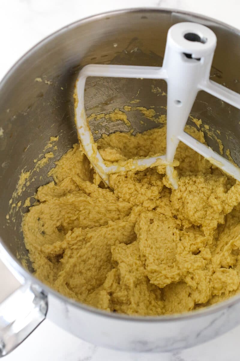 Mixing eggs and vanilla into creamed butter and sugars to make cookie dough.