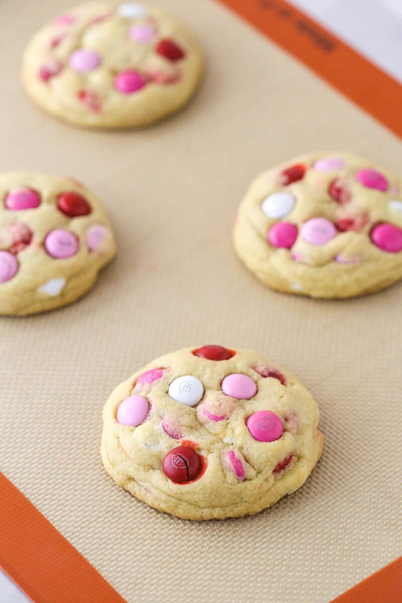 Valentine's Day M&M cookies on a silicone baking mat.