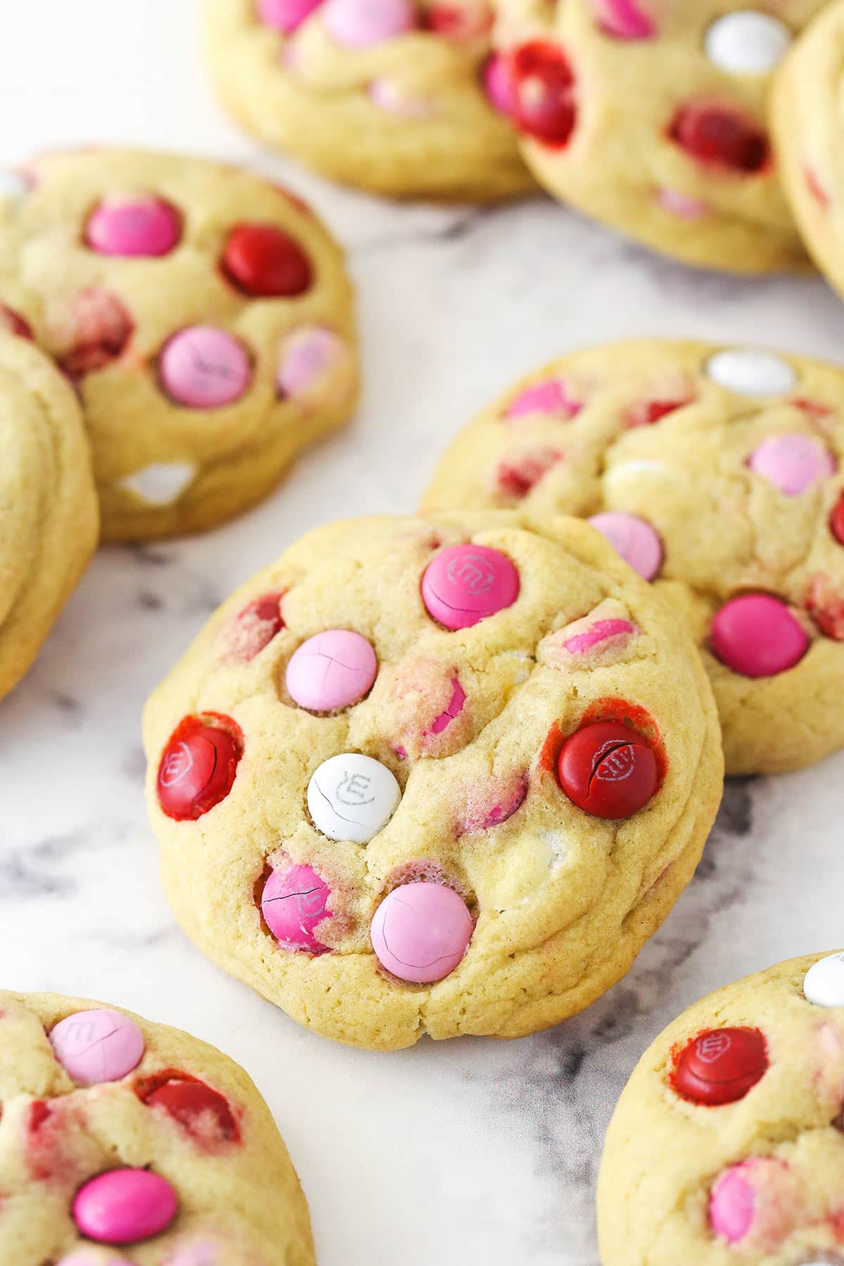 Valentine's Day M&M cookies spread out on a work surface.