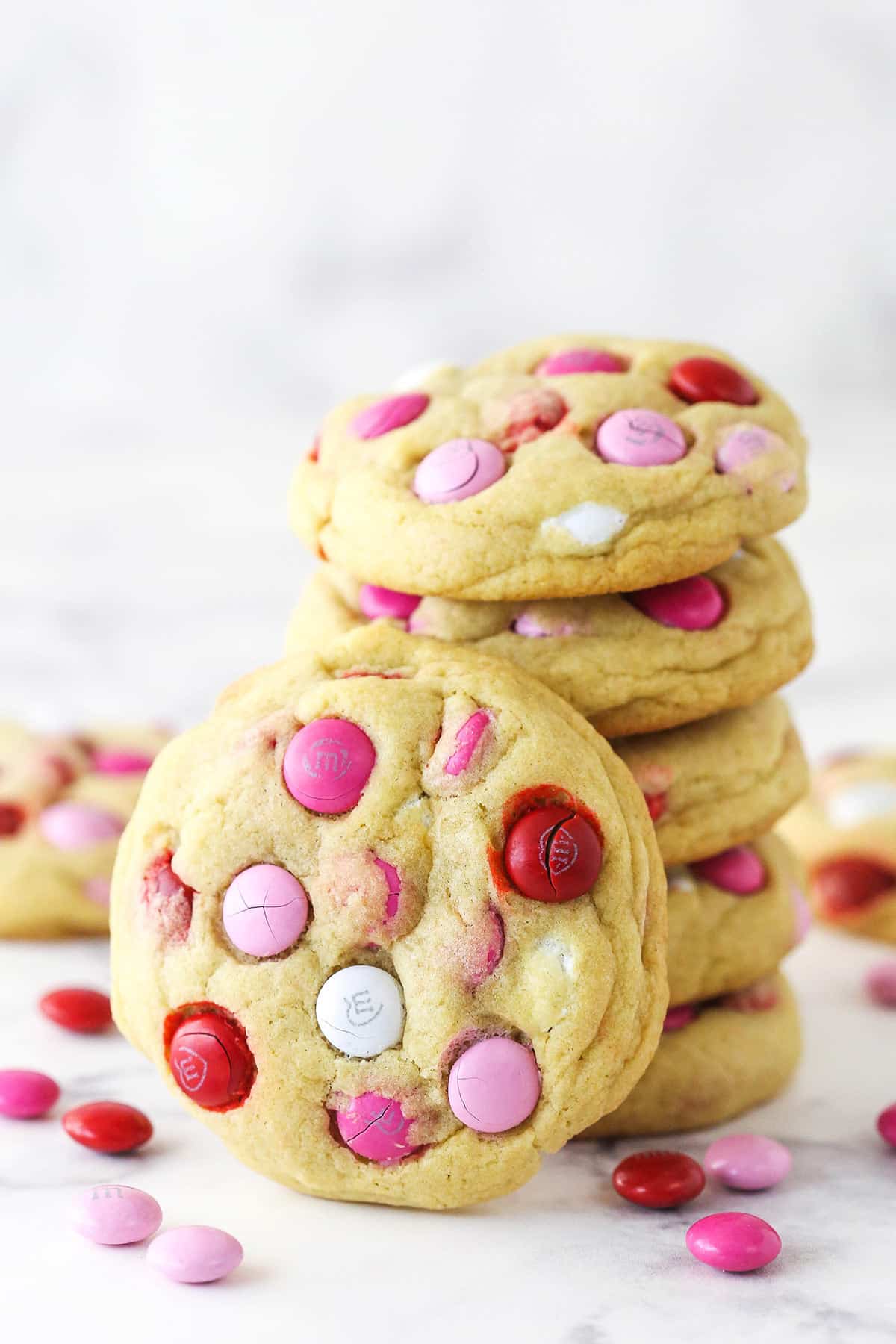 A stack of Valentine's Day M&M cookies with a cookie standing up against it.