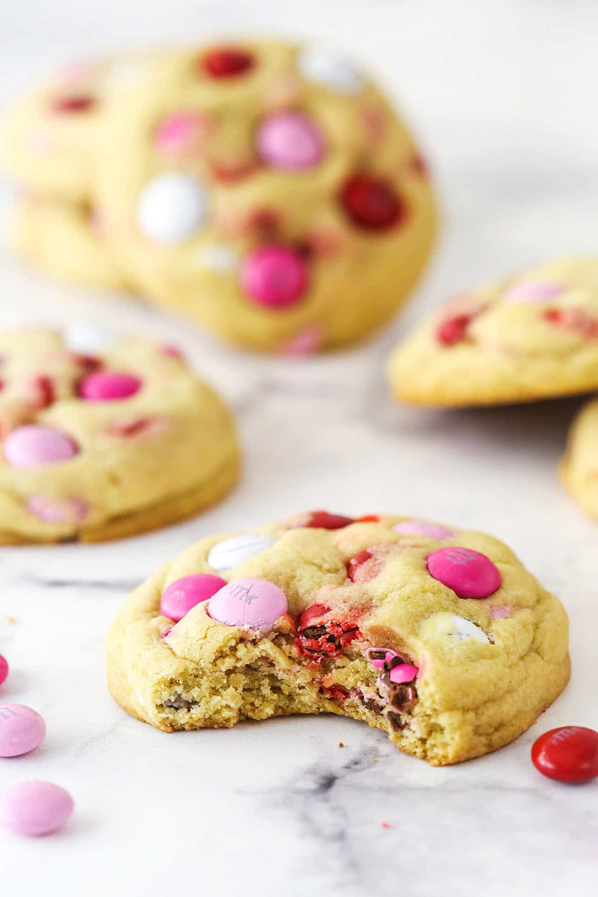 A Valentine's Day M&M cookie with a bite taken out of it.