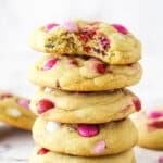 A stack of Valentine's Day M&M cookies. The top cookie has a bite taken out of it.