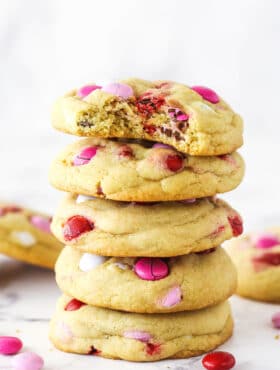 A stack of Valentine's Day M&M cookies. The top cookie has a bite taken out of it.