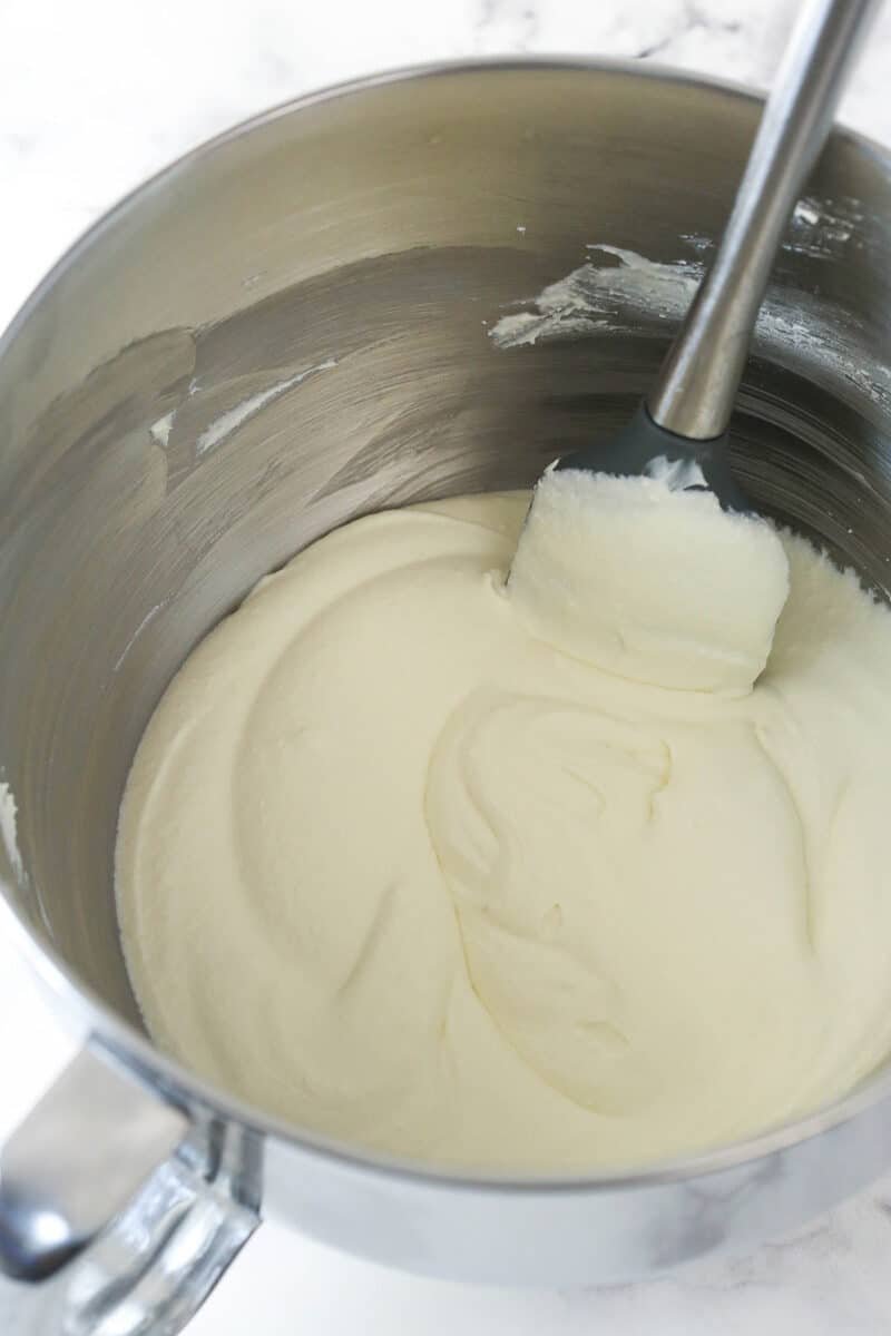 Mixing together ricotta cheese, mascarpone cheese, and vanilla extract.