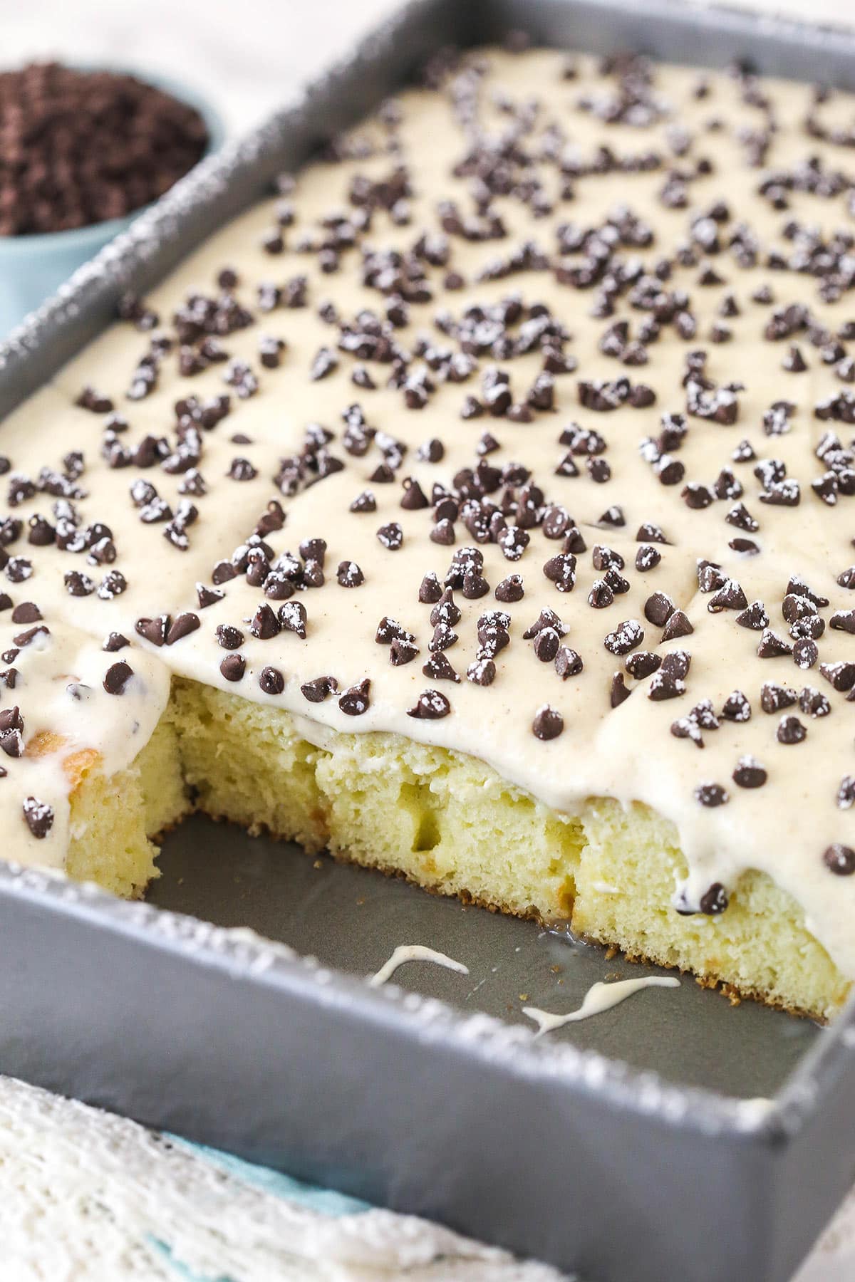 Cannoli poke cake in a baking pan with slices taken out of it.