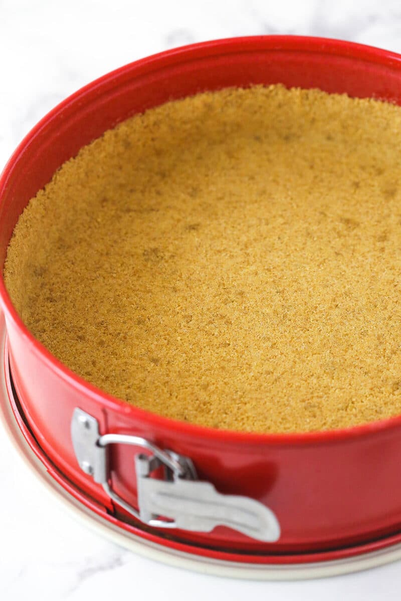 Pressing graham cracker crust into the bottom and up the sides of a springform pan.