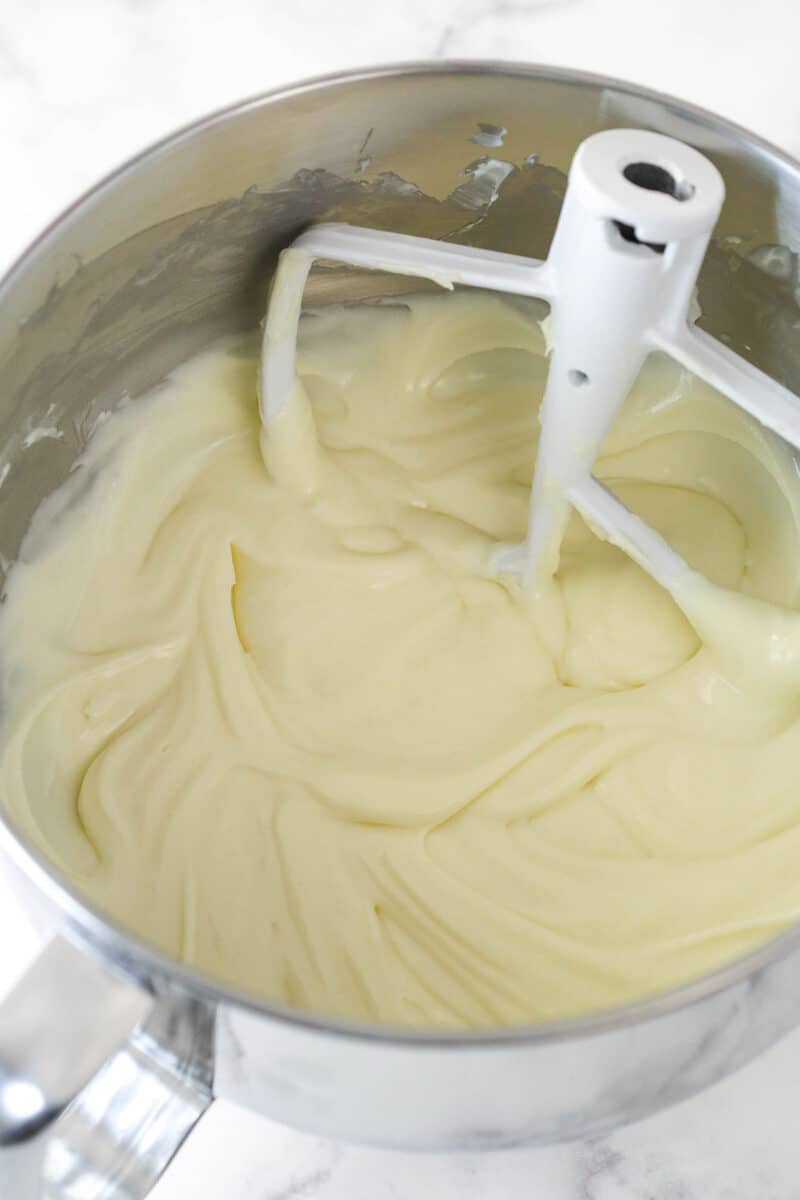 Stirring sour cream, cream of coconut, coconut extract, and vanilla extract into cheesecake batter.